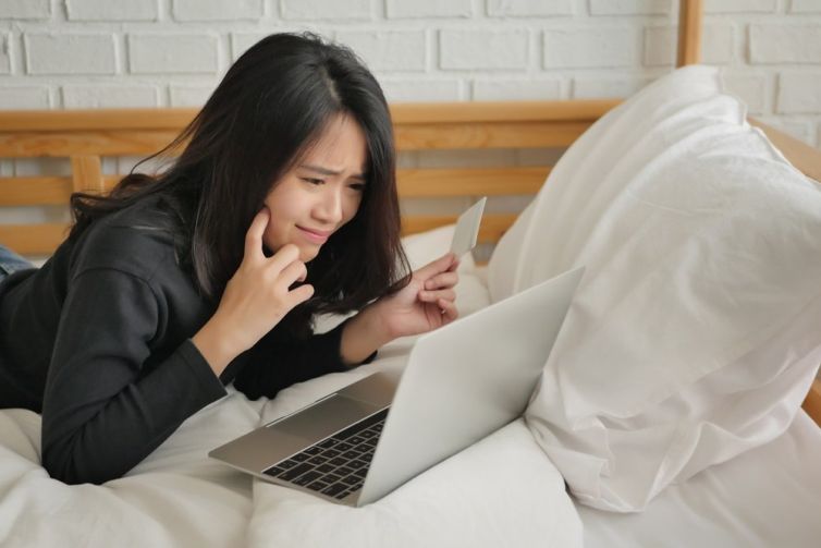 Person laying on bed looking at open laptop
